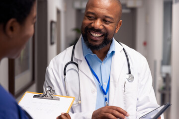 Smiling african american male and female doctor talking in hospital corridor