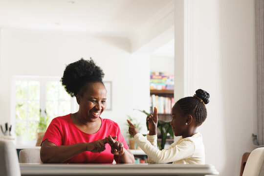 Happy african american grandmother and deaf granddaughter using sign language