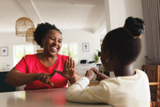 Happy african american grandmother and deaf granddaughter using sign language