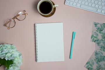A blank notebook with office items over the pink background. 