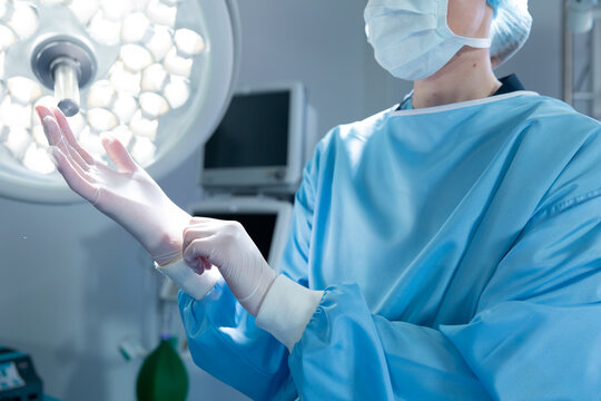 Caucasian female surgeon in an operating theatre, wearing medical gloves