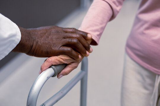 Close up of african american doctor and senior caucasian patient holding hands