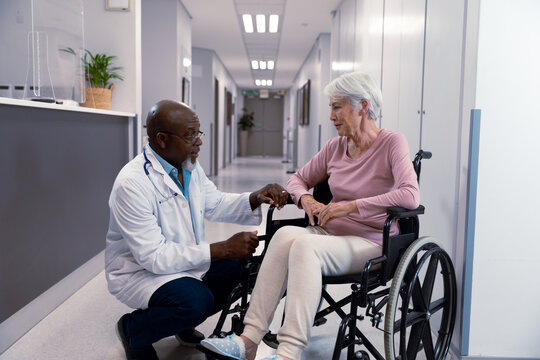 African american doctor talking to senior caucasian patient sitting in wheelchair
