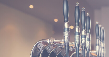 Image of close up of taps of beer and interior of traditional bar