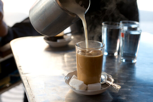 Hot milk is poured into coffee at a cafe in Asilah, Morocco.