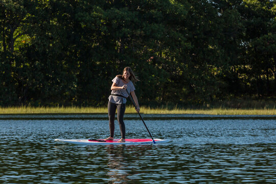 Front view of woman standing up paddle boarding on Essex River at Cox Reservation in Essex, Massachusetts