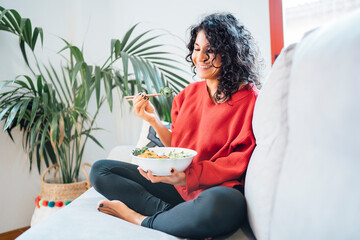 Brunette woman eating a healthy green salad.