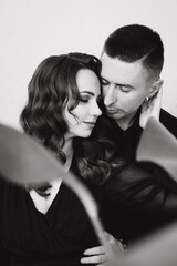 Stylish beautiful photo session in a photo studio of a luxurious couple in a black suit and black dress, where a girl with red hair. They hug.