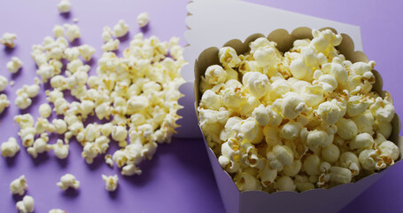 Image of close up of two white popcorn tubs on purple background