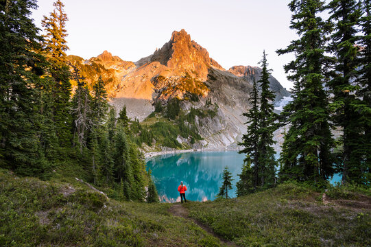 Female In Red Jacket Next To Gorgeous Turquoise Alpine Lake At Sunset