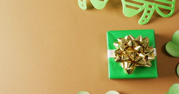 Video of st patrick's green shamrock, present and glasses with copy space on orange background