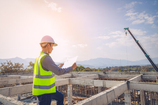 Asian engineer holding a flipchart working outdoors building side sunset background