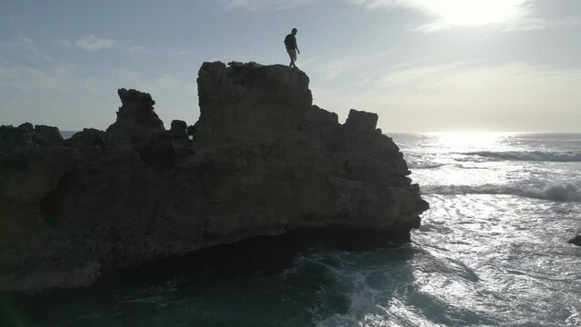 Young Man Jumps off Rocky Cliff into the Ocean, Swims to Shore.  Daytime.  Tripod.