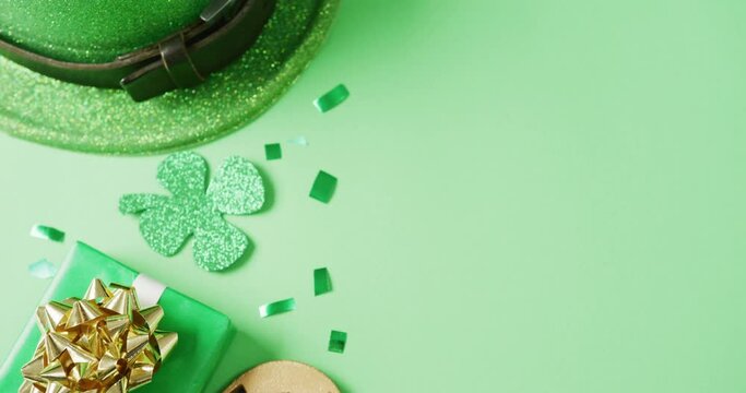 Video of st patrick's green shamrock leaf, present and hat with copy space on green background