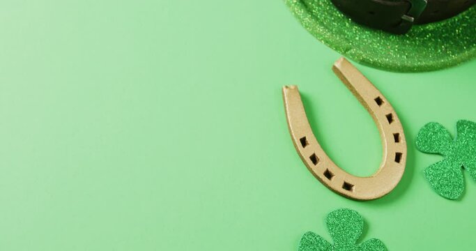 Video of st patrick's green shamrock leaf, horse shoe, hat with copy space on green background