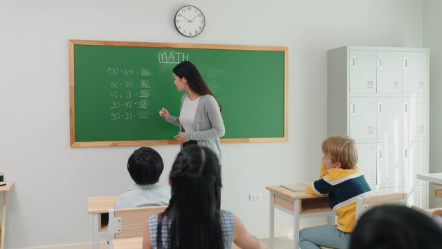 Elementary school students are sitting in the classroom at school and answering teacher questions in mathematics