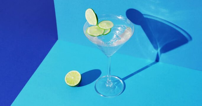 Close up of transparent drink with lime on blue background