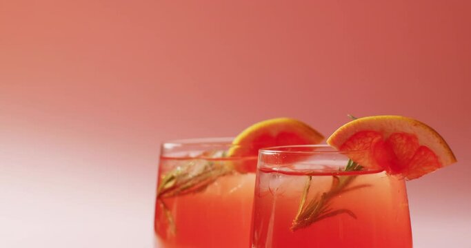 Close up of drinks with oranges on pink background
