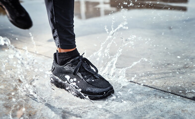 Feet splash water in street, person running in the rain and shoes in puddle of Seattle road for...
