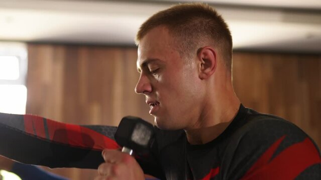 Male boxers training activities with dumbbells at fitness club. Male fighters exhausting box training kicks with dumbbells. Adult and fit men having evening workout indoor. Fitness and sport concept