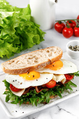 Sandwich, toast with eggs, bacon, green lettuce. Fresh and healthy homemade toasted sandwich.