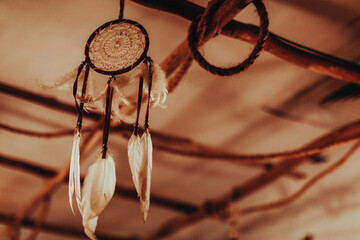 Dreamcatcher hanging in boho beige interior in the evening light. Magical and ritual ornament