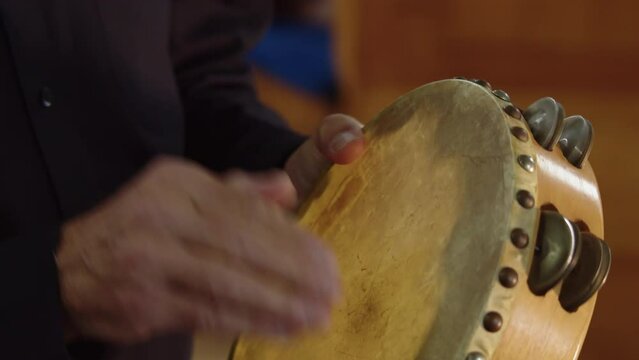 Close up man playing the tambourine percussion instrument in orchestra