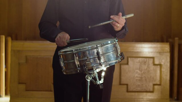 Male percussionist in smart suit plays the snare drum in concert hall