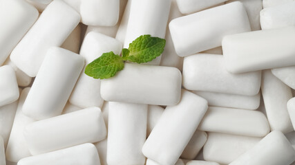 Tasty chewing gums and fresh mint leaves as background, top view - obrazy, fototapety, plakaty
