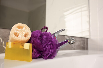 Purple shower puff, loofah sponge and soap on sink in bathroom, space for text