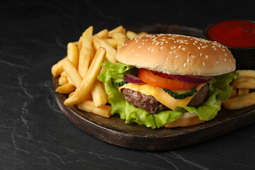 Delicious burger and french fries served on black table, closeup