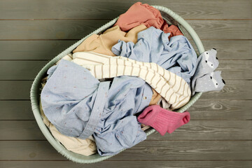 Fototapeta na wymiar Laundry basket with clothes on dark grey wooden floor, top view