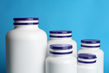 White medical bottles on light blue background, closeup