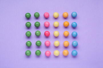 Many bright chewy gumballs on lilac background, flat lay