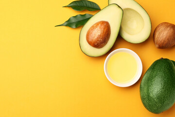 Cooking oil in bowl and fresh avocados on yellow background, flat lay. Space for text
