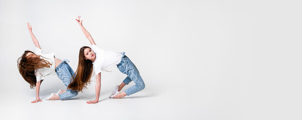 teenagers girls in jeans and white t-shirts synchronously perform dance moves on a white background. Banner. Space for text