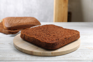 Fototapeta na wymiar Layers of homemade chocolate sponge cake on white wooden table