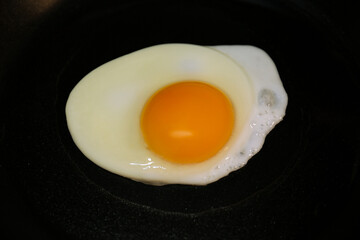 Cooking egg for tasty breakfast in frying pan, closeup