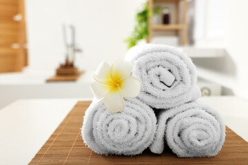 Rolled towels on white table in bathroom. Space for text