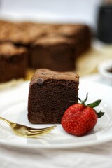 homemade Taiwanese Castella cake slice with strawberries on white plate. chocolate cake soft and delicious with ingredient: egg, cocoa, milk, flour and chocolate chips sprinkles. 
