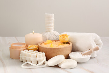 Sea salt, different spa products and beautiful rose on white marble table