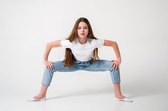 A teenage girl in jeans and a white T-shirt performs dance moves. White background