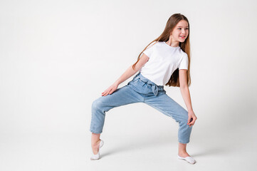 A teenage girl in jeans and a white T-shirt performs dance moves. White background