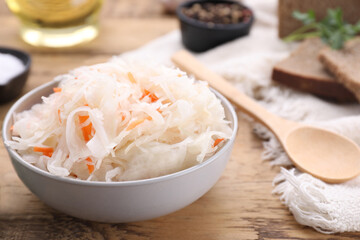 Bowl of tasty sauerkraut on wooden table, closeup