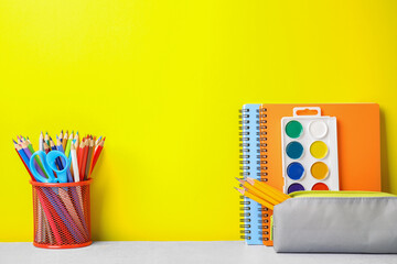 Different school stationery on white table against yellow background, space for text. Back to school