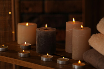 Spa composition with burning candles and towels on wooden table in wellness center