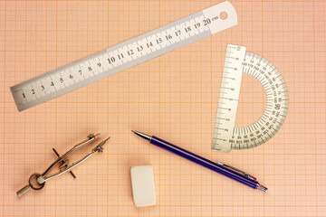 Drawing accessories lie on a sheet of graph paper