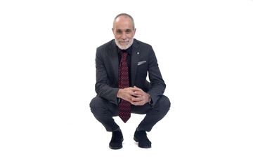 front view of a man with suit squatting and looking at camera on white background