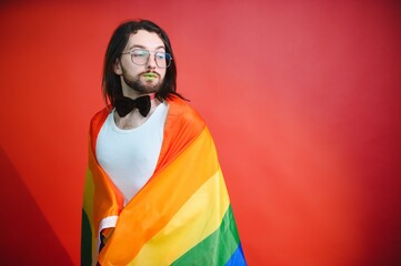 Gay man hold rainbow striped flag isolated on colored background studio portrait. People lifestyle fashion lgbtq concept