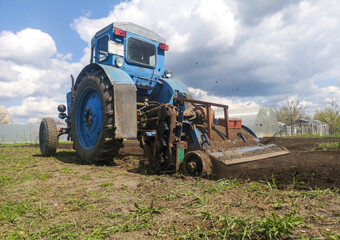 The tractor plows the soil on the field